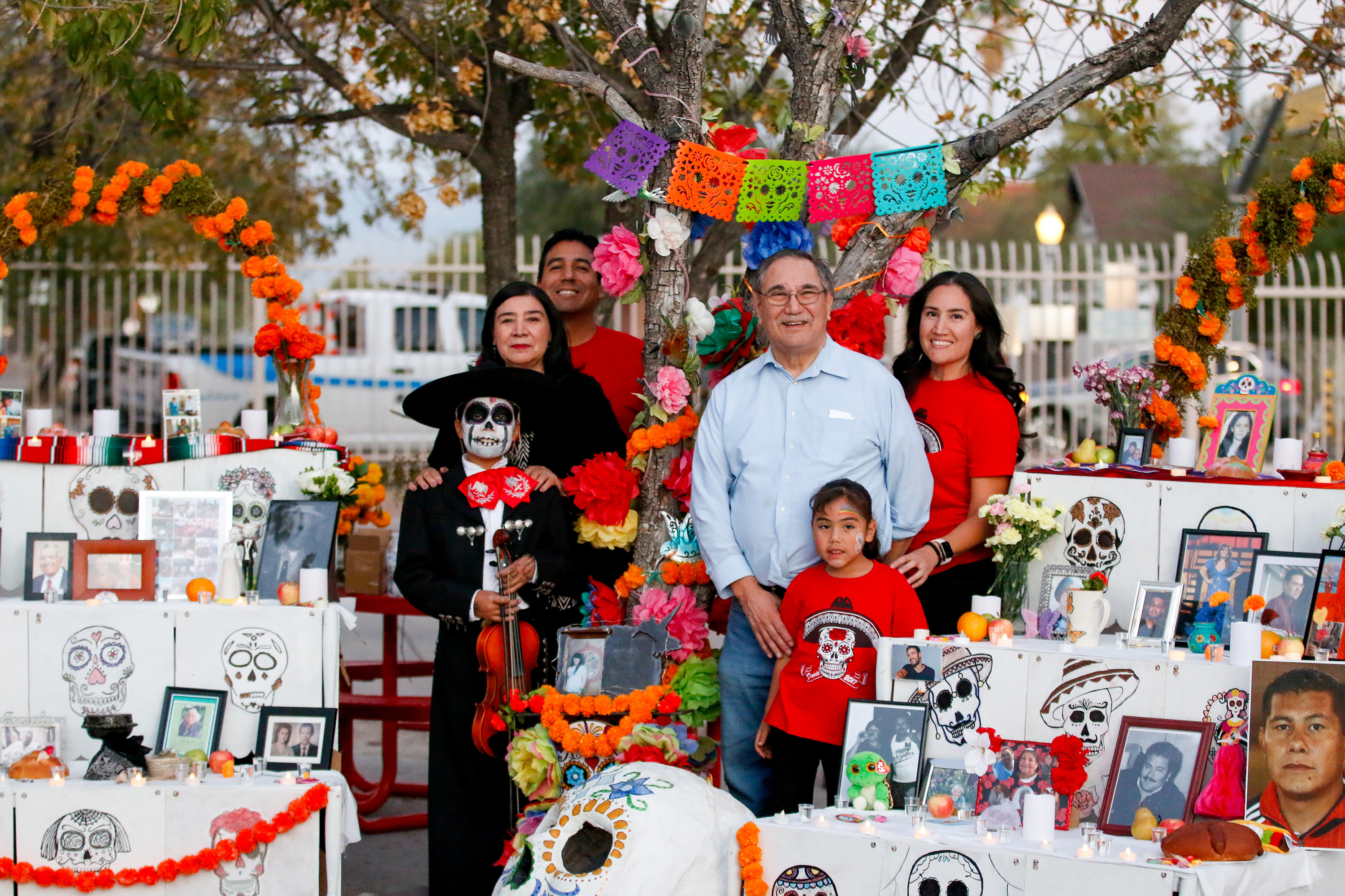 A family stands by the ofrendas