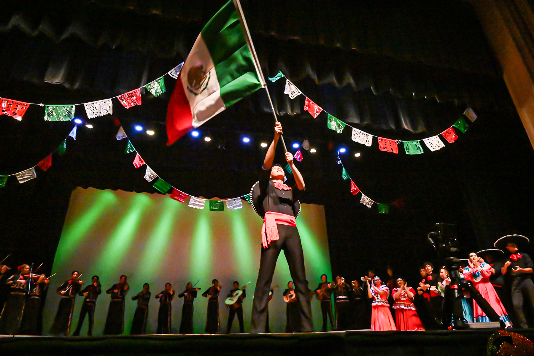 A mariachi performer holds up the Mexican flag