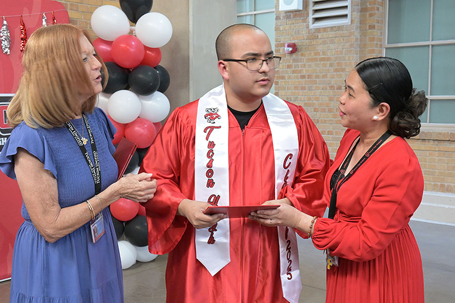 A teen boy in a red gown gets his diploma
