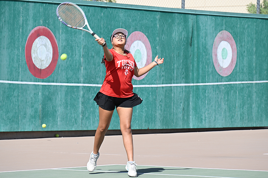 A girl swings her racquet at the tennis ball