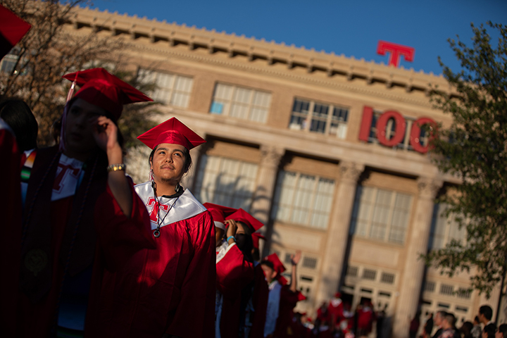 A teen boy looks up as he and other graduates proceed into the stadium