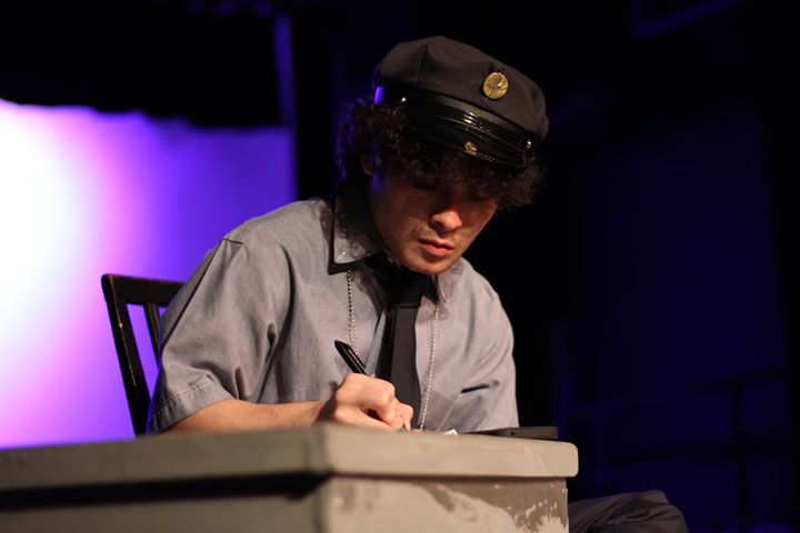 A teen boy dressed as a detective writes a note