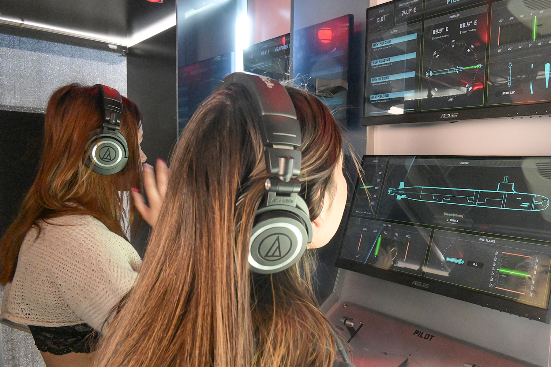 Two girls in headphones look at digital displays