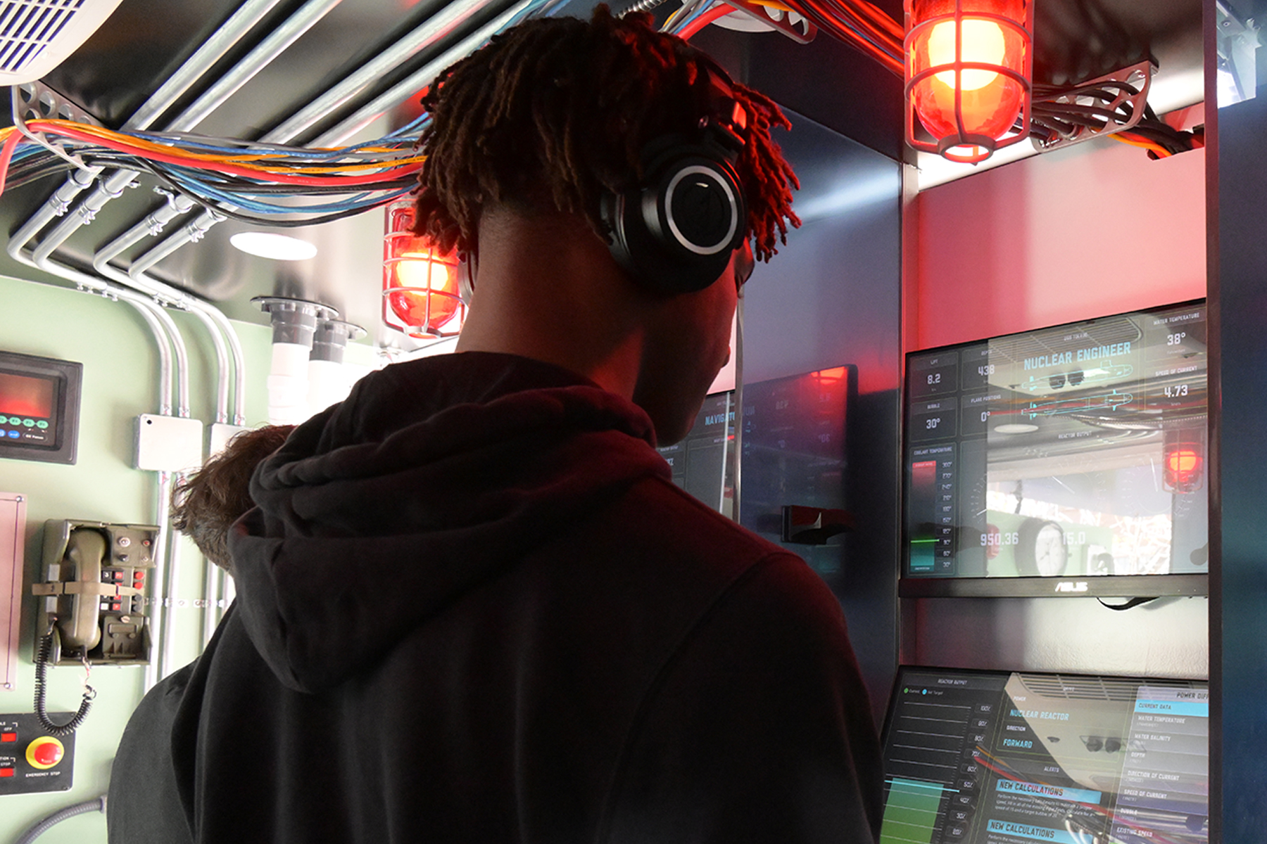 A boy in a headset looks at digital display screens