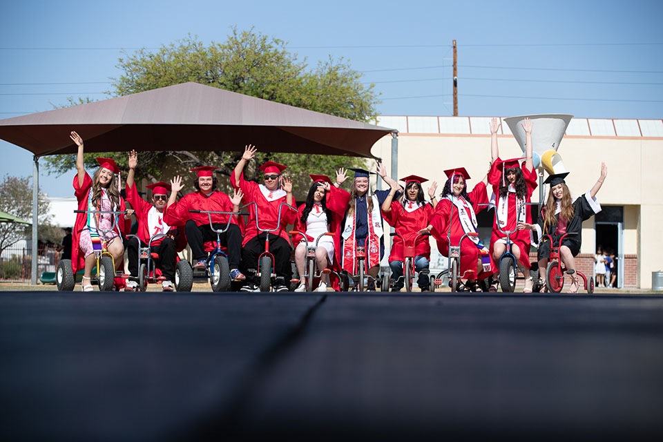 Tucson High students ride around on tricycles in their caps and gowns