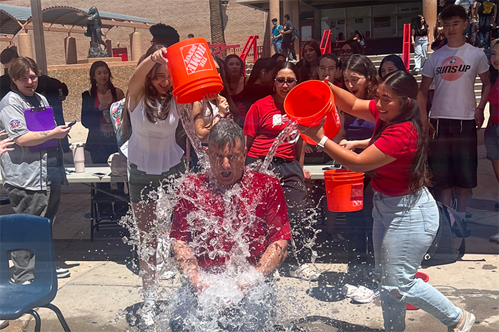 Students dump buckets of water on a teacher's head
