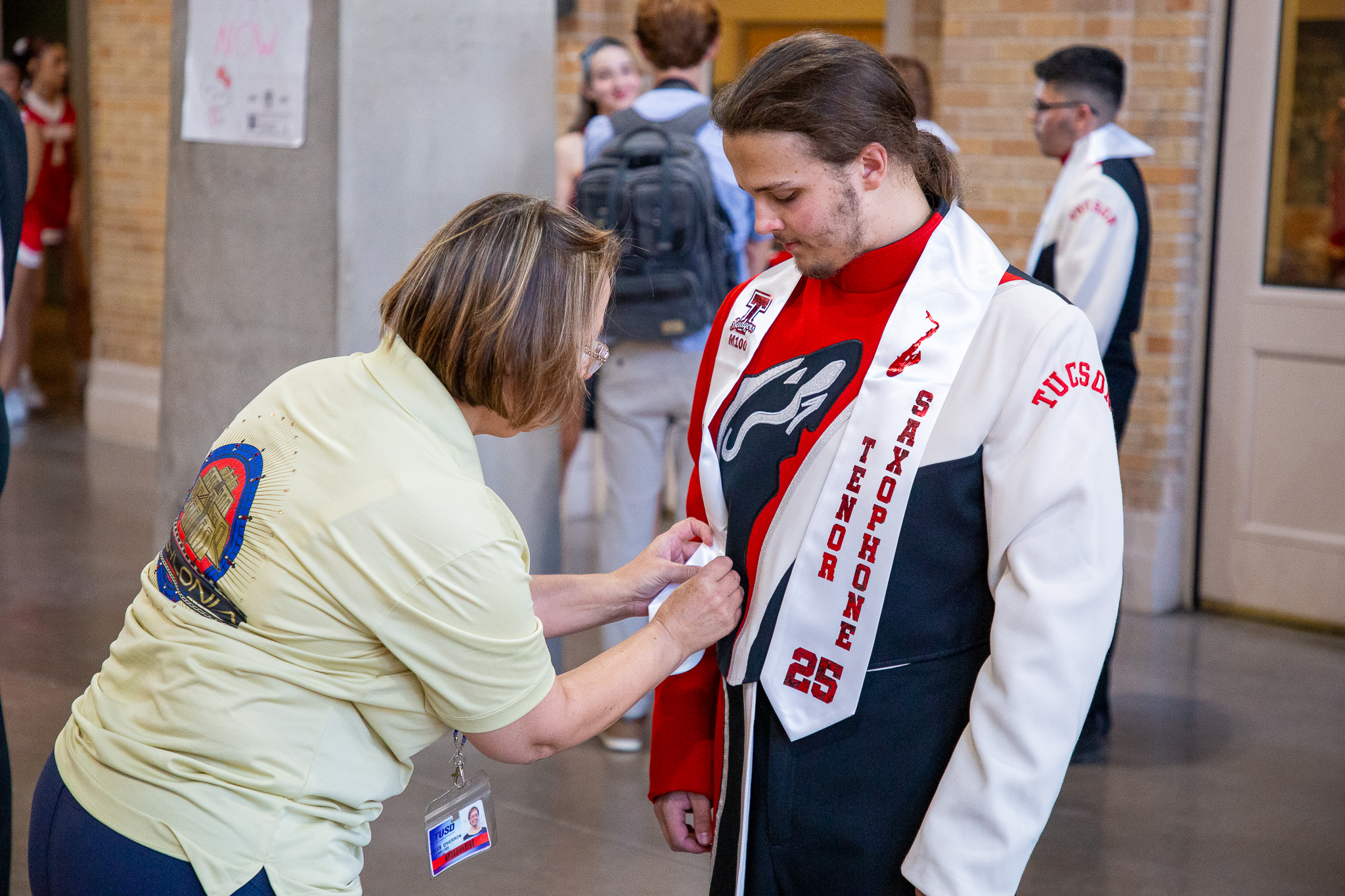 A band volunteer pins a sash on a tenor saxophone player