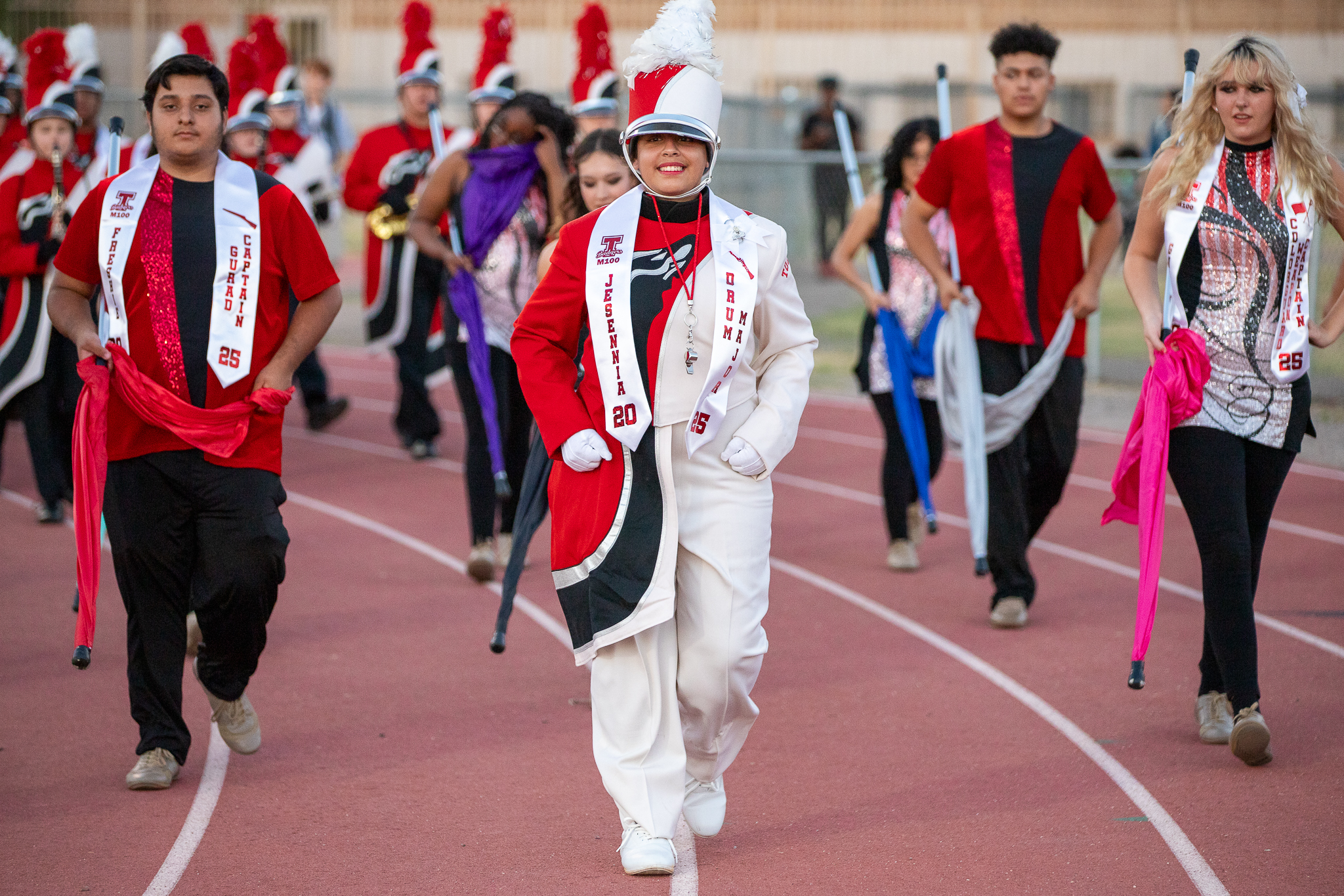 The drum major smiles as she leads the band around the track