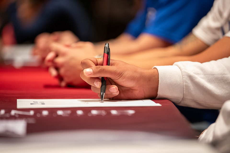 Closeup of a hand holding a pen signing a letter of intent