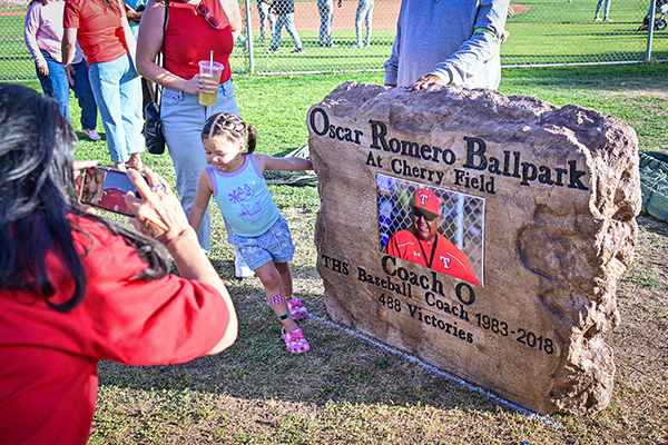 A woman takes a picture of a little girl in front of the Oscar Romero Ballpark sigmn