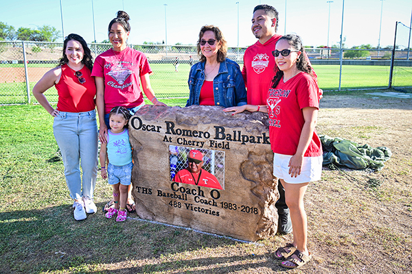 A group poses in front of the Oscar Romero sign