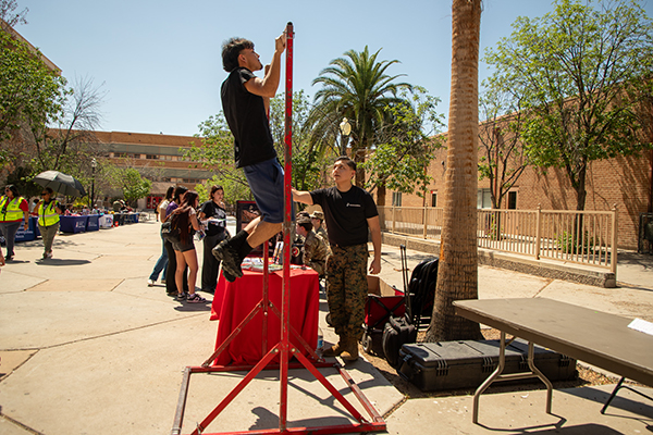 A teen boy does a pullup at the Marines table at the career fair