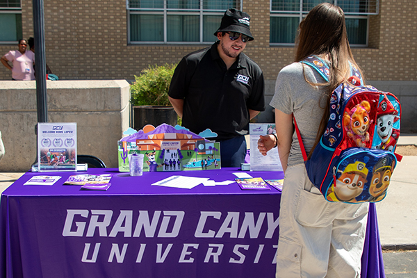 A man from Grand Canyon University talks to a teen girl at his table
