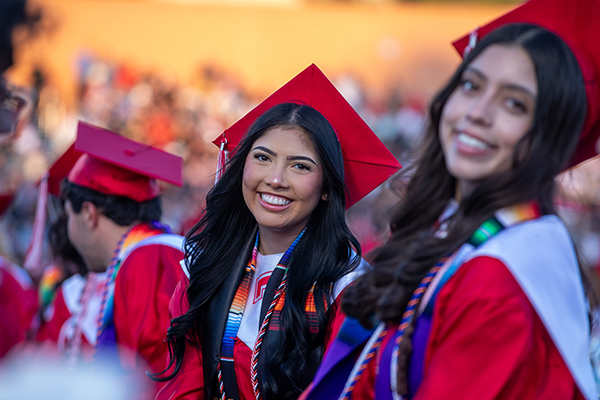 Two teen girls smile during the graduation ceremony