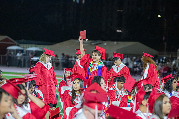 A graduate holds up his diploma during the ceremony