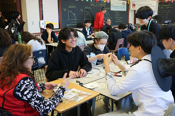 Students sit around a table working on a craft project