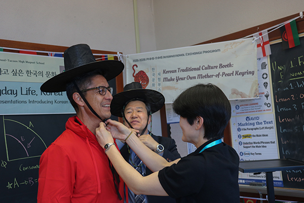 A woman ties a black hat around a man's head