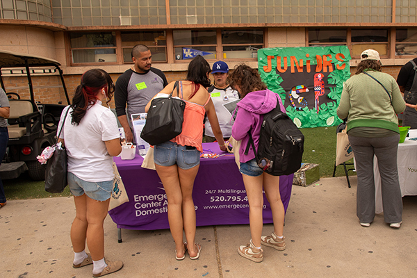 Three teen girls talk to two representatives at a table