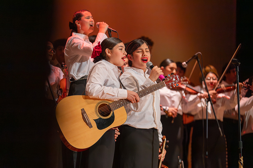 Mariachi students sing into microphones