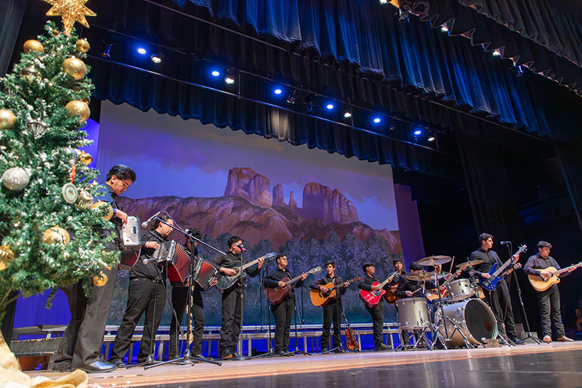 A student mariachi group performs next to a Christmas tree and in front of a Sedona backdrop
