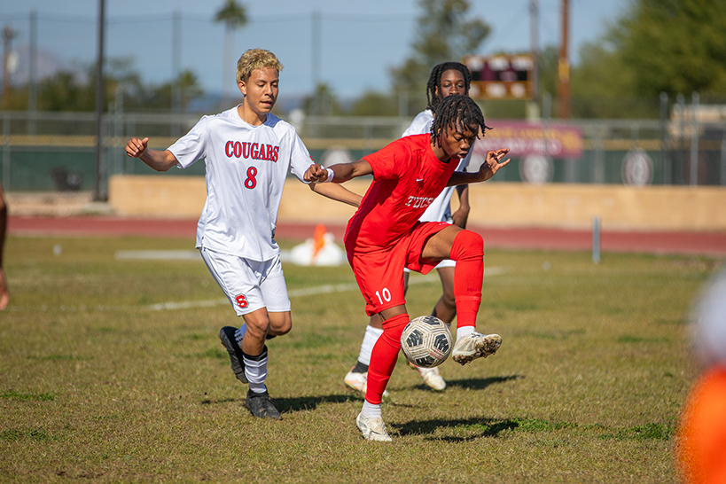 A Tucson High player kicks the soccer ball between his legs to keep it from his opponents