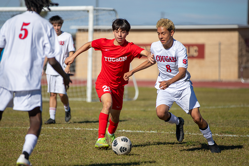 A Tucson High player puts his arm out to block a Sahuaro opponent from getting to the soccer ball