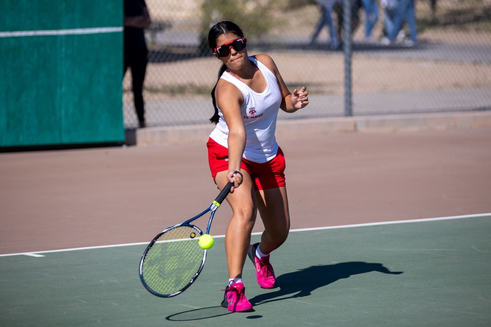 A THMS girls tennis player aims her racquet low to hit the ball.
